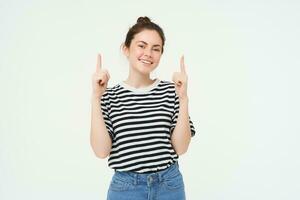 estilo de vida y anuncio concepto. joven sonriente mujer, moderno chica, señalando dedo a promoción, demostración bandera, sitio con texto, aislado en blanco antecedentes foto