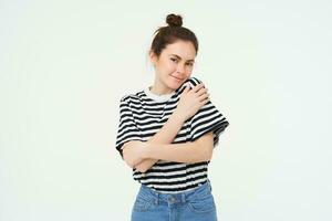 Image of tender, beautiful brunette girl, hugging herself, concept of selfcare and love, standing over white background photo