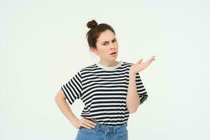 Portrait of angry woman complaining, raising one hand and shrugging looking frustrated, waiting for explanation, doesnt udnerstand smth, standing over white background photo