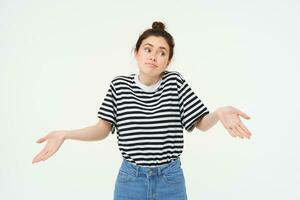 Image of confused brunette girl shrugging shoulders, looks puzzled, isolated over white background photo