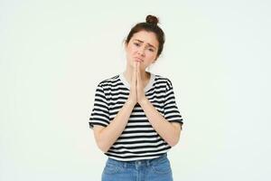 Portrait of sad girl begging you, asking for help, standing in pleading pose, white background photo