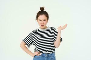 Portrait of angry woman complaining, raising one hand and shrugging looking frustrated, waiting for explanation, doesnt udnerstand smth, standing over white background photo