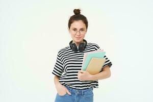 Student lifestyle and people concept. Portrait of young woman in glasses, teacher or college girl with books and study material, posing over white background photo