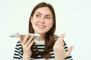 Portrait of happy young woman, student recording voice message, holding smartphone near lips, talking into mobile phone speakerphone, explaining something, singing, translating her words photo