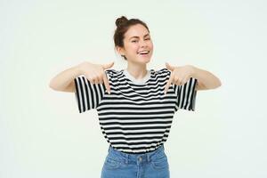 Carefree woman showing advertisement below, follow link on bottom, standing over white background photo