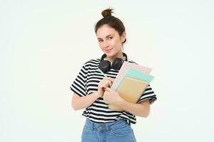 imagen de joven mujer, tutor con libros y cuadernos, vistiendo auriculares terminado su cuello, aislado en blanco antecedentes. estudiante estilo de vida concepto foto