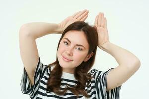 Image of beautiful young woman, posing with animal ears on head and smiling, making cute face, white background photo