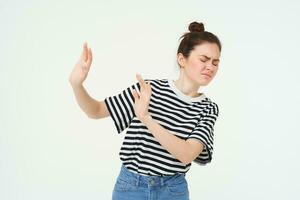 Portrait of woman looking disgusted, expressing dislike and aversion, raising hands to block something, rejecting offer, refusing, standing over white background photo