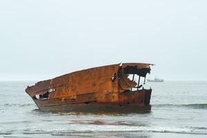 rusty shipwreck against a foggy seascape with a sailing ship photo