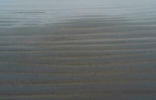 black volcanic sand beach with wave patterns photo