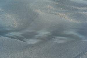 blurred natural background, water flows along the beach from black volcanic sand photo