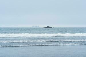 landscape with a sea rock and a sailing ship in the distance photo