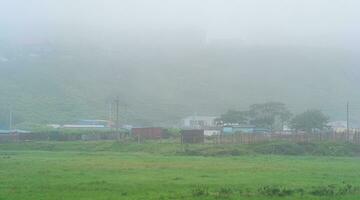 rural landscape with vegetable gardens and barns in thick fog photo