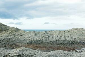 rocky seashore made of columnar granite, hardened lava, resembling scales or cobblestone pavement, coast of Kunashir island photo