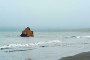 oxidado naufragio, el destrucción de un Embarcacion apagado el costa en contra el fondo de un brumoso mar foto