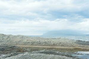 rocky seashore made of columnar granite, hardened lava, resembling scales or cobblestone pavement, coast of Kunashir island photo