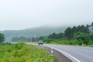 highway through foggy wooded hills on Kunashir island photo