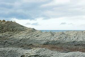rocky seashore made of columnar granite, hardened lava, resembling scales or cobblestone pavement, coast of Kunashir island photo