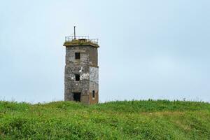 abandoned lighthouse on a grassy seashore photo