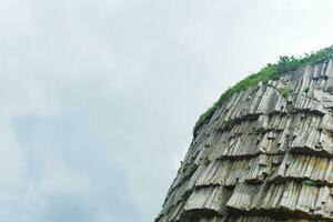 top of columnar volcanic basalt cliff against the background of the sky with clouds photo