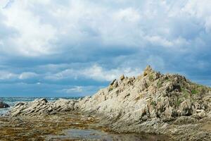 ocean shore with rocks of columnar basalt, Cape Stolbchaty on Kunashir Island photo