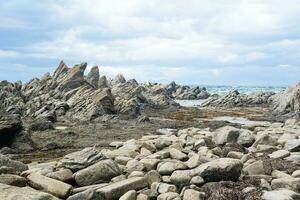 sharp jagged basalt rocks on the sea coast, Cape Stolbchaty on Kunashir Island photo