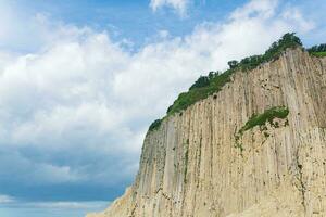 top of columnar volcanic basalt cliff against the background of the sky with clouds photo