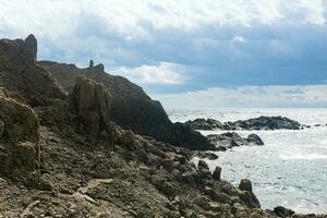 ocean shore with rocks of columnar basalt, Cape Stolbchaty on Kunashir Island photo