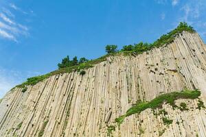 top of columnar volcanic basalt cliff against the background of the sky with clouds photo