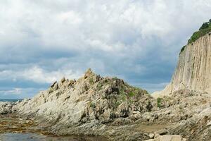 ocean shore with rocks of columnar basalt, Cape Stolbchaty on Kunashir Island photo