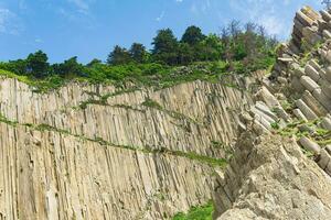 natural landscape with a sheer cliff folded columnar basalt on the seashore photo