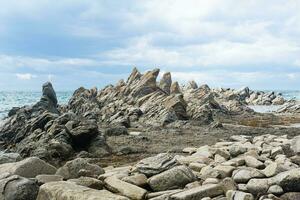 basalt rocks on the sea coast, Cape Stolbchaty on Kunashir Island photo