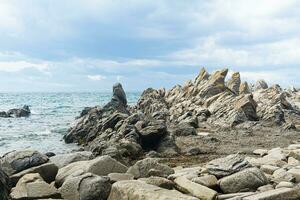 basalt rocks on the sea coast, Cape Stolbchaty on Kunashir Island photo