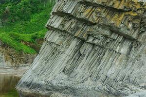 foot of a coastal cliff composed of columnar basalt, on the island of Kunashir photo