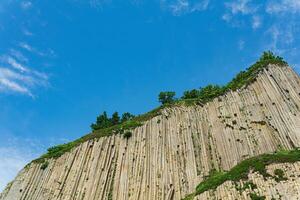 top of columnar volcanic basalt cliff against the background of the sky with clouds photo