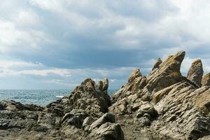 basalt rocks on the sea coast, Cape Stolbchaty on Kunashir Island photo