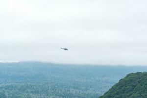 cloudy landscape with distant helicopter over misty hills photo