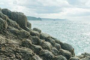 coastal cliff formed by solidified lava close-up against the background of a distant sea shore photo