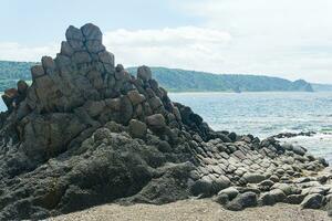 gray basalt rocks against a blurred coastal seascape photo