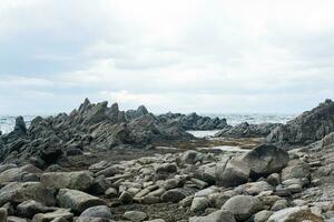 sharp jagged basalt rocks on the sea coast, Cape Stolbchaty on Kunashir Island photo