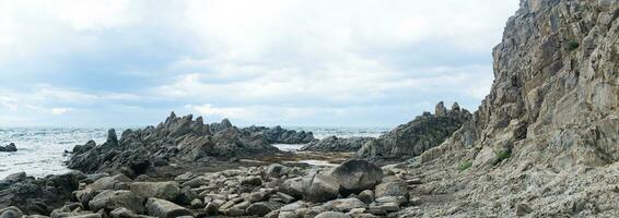 sharp jagged basalt rocks on the sea coast photo