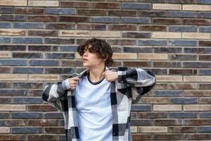 young man posing against a brick wall photo