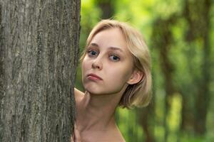 hermosa joven mujer siguiente a el árbol en el bosque foto