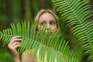 joven hermosa mujer entre el helecho hojas en el bosque foto