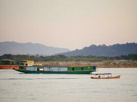 slow boat cruising along the Mekong River, Local boat moving on Mekong river between the border of Thailand and Laos, Boat transport on the river, transport ship photo