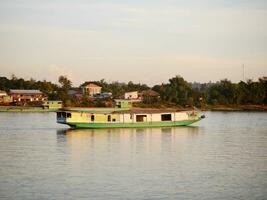 slow boat cruising along the Mekong River, Local boat moving on Mekong river between the border of Thailand and Laos, Boat transport on the river, transport ship photo