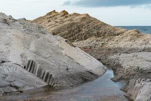 coastal cliffs formed by columnar basalt at low tide photo