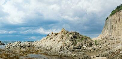 ocean shore with rocks of columnar basalt, Cape Stolbchaty on Kunashir Island photo