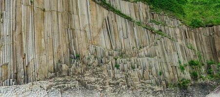 panorama of the coastal landscape of Kunashir Island near Cape Stolbchaty with columnar basalt rocks covered with vegetation photo