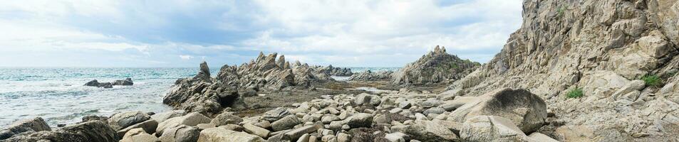 sharp jagged basalt rocks on the sea coast, Cape Stolbchaty on Kunashir Island photo